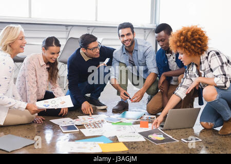 Creative business team discussing over documents on floor at office Stock Photo