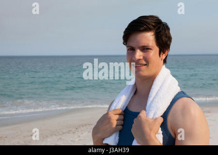 Portrait of smiling man standing on beach with towel around his neck Stock Photo