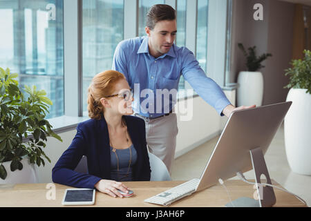 Executives having discussion over personal computer at desk in office Stock Photo