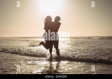 Silhouette couple enjoying on shore at beach during sunny day Stock Photo