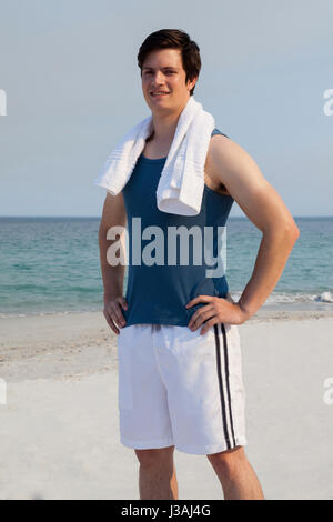 Portrait of smiling man standing on beach with towel around his neck Stock Photo