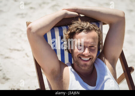 High angle portrait of young woman relaxaing on lounge chair at beach during sunny day Stock Photo