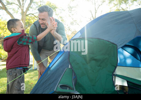 Father and son giving a high five after setting up the tent at campsite Stock Photo