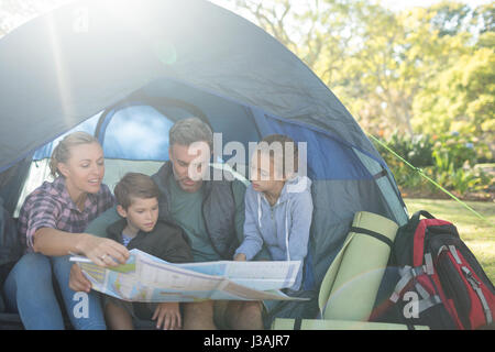 Family reading the map in tent on a sunny day Stock Photo