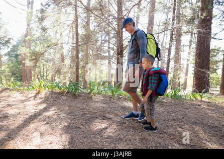 Side view of father and son holding hands hiking in forest Stock Photo