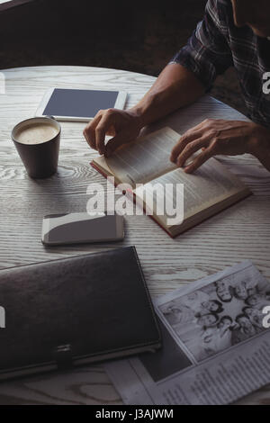 Mid section of businessman reading magazine on table in office Stock Photo