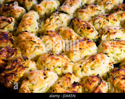 Culinary products from sliced zucchini with cheese, spices and herbs are laid out on baking tray and baked in the oven covered with a crispy glaze Stock Photo