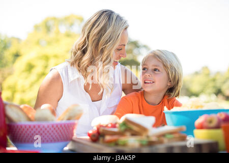 Mother and son interacting with each other while having meal in park on a sunny day Stock Photo