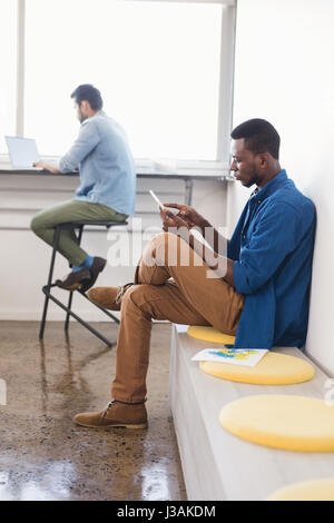 Side view of creative businessman using mobile phone while sittig at office Stock Photo