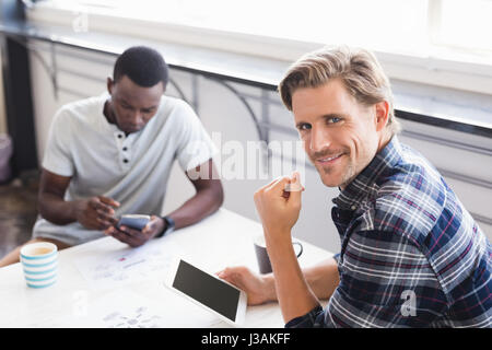 Portrait of businessman sitting with colleague at table in office canteen Stock Photo