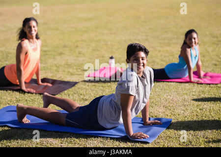 Portrait of children and instructor practicing yoga on mat at park Stock Photo
