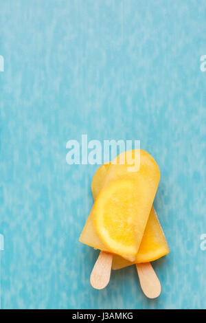 Fruit ice cream lollies on a blue surface. Top view, copy space Stock Photo