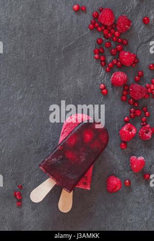 Ice cream lollies and frozen fruit on  dark background top view copy space Stock Photo