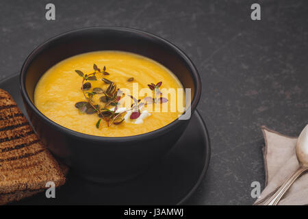 Pumpkin soup with blue cheese, thyme and slice of bread. Macro, selective focus, blank space Stock Photo