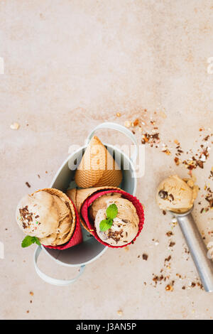 Creamy  ice cream in wafer cones served in vintage metal bowl with spoon over rustic surface.  Top view, blank space Stock Photo