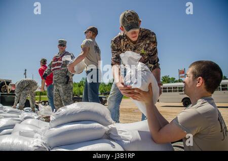 Missouri National Guardsmen and student volunteers work to build a support wall with sandbags to support a levee against floodwaters May 2, 2017 in Poplar Bluff, Missouri. Historic flooding has swamped towns across Arkansas and Missouri with at least 20 people reported dead. Stock Photo