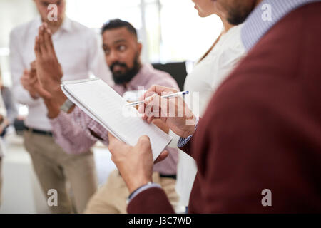 business team and man writing to notepad at office Stock Photo