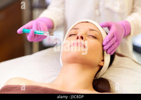 beautician doing beauty injection to woman lips Stock Photo