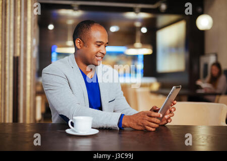 Image of happy young man using digital tablet in cafe Stock Photo