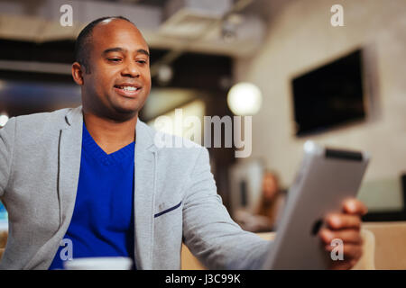 Image of happy young man using digital tablet in cafe Stock Photo