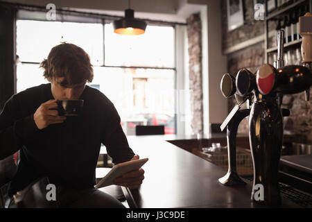 Man using digital tablet while having coffee in cafÃƒÂ© Stock Photo