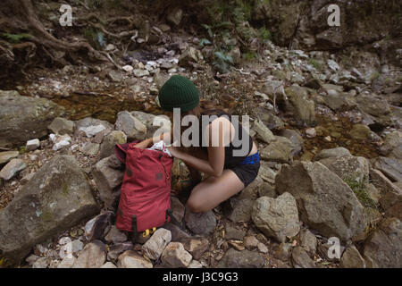 Young female hiker checking her bag in the forest Stock Photo