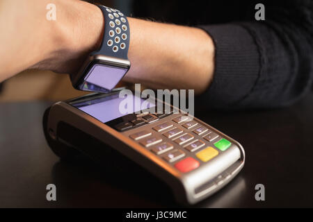 Close-up of man paying through smartwatch using NFC technology in cafÃƒÂ© Stock Photo