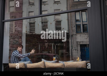 Thoughtful man using mobile phone in cafÃƒÂ© Stock Photo