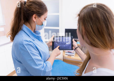 dentist showing teeht x-ray on tablet pc computer to woman patient at dental clinic office Stock Photo