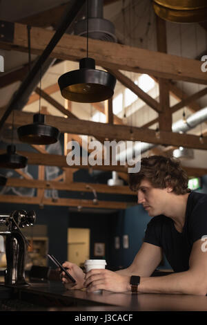Man using mobile phone while having coffee in restaurant Stock Photo