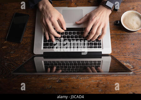 Hands of man using laptop while having coffee in cafÃƒÂ© Stock Photo