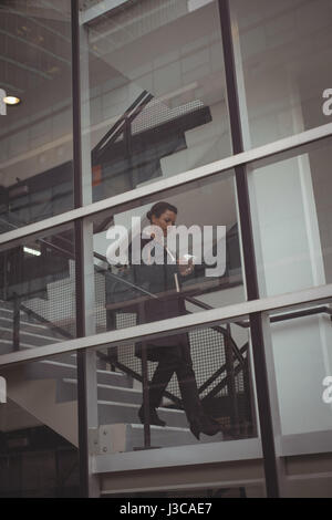 Businesswoman using mobile phone seen through glass window Stock Photo