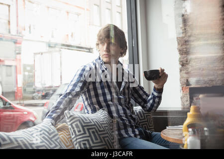 Thoughtful man sitting on sofa and having coffee in cafÃƒÂ© Stock Photo