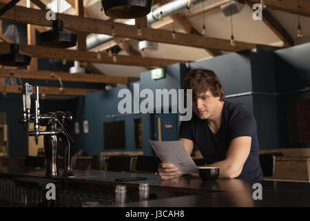 Man looking at menu card while having coffee in restaurant Stock Photo