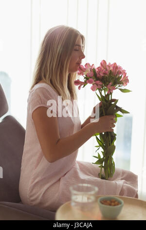Beautiful woman smelling flower at home Stock Photo