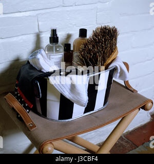 Washing products in a striped tin bucket on a folding stool Stock Photo