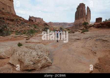 Two men hiking Park Avenue in Arches National Park, Moab, Utah Stock Photo