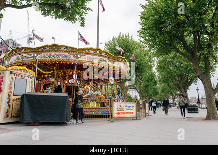 A merry-go-round and the London Eye ferris wheel on Southbank in London, one of the city's most popular areas. Stock Photo