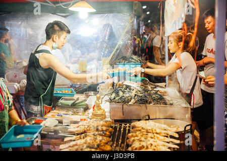 CHIANG MAI, THAILAND - AUGUST 27: Food vendor cooks and sells fish and seafood at the Saturday Night Market (Walking Street) on August 27, 2016 in Chi Stock Photo