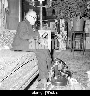 French actor, playwright and director Sacha Guitry in the living room of his Paris apartment located 18 avenue Elisée Reclus. c.1955 Photo Georges Rétif de la Bretonne Stock Photo