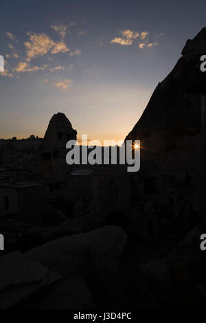 View of silhouetted rock-cut cave dwellings in Goreme at sunset, Cappadocia region, Turkey, Western Asia. Stock Photo
