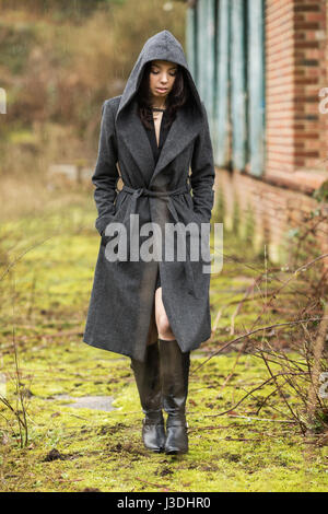 A young woman walking in the countryside dressed in a hooded coat Stock Photo