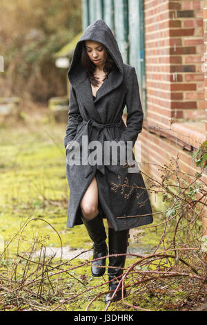 A young woman walking in the countryside dressed in a hooded coat Stock Photo