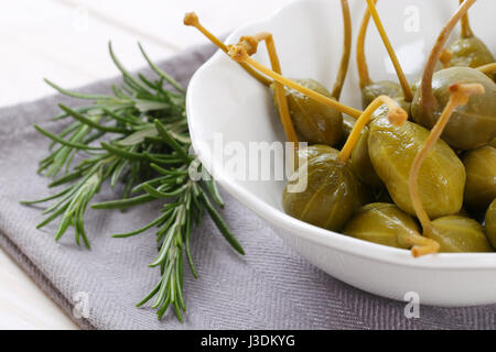 bowl of pickled caper berries on grey place mat Stock Photo