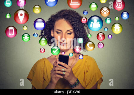 communication technology mobile phone high tech concept. Annoyed skeptical woman using texting on smartphone application icons flying out of cellphone Stock Photo