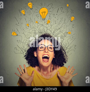 Closeup super excited happy screaming woman with many light idea bulbs above head celebrates success looking up on gray wall background Stock Photo