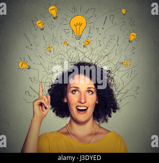 Closeup excited woman with many ideas light bulbs above head looking up pointing finger up isolated on gray wall background. Eureka creativity concept Stock Photo