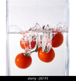 Juicy small cherry tomato dropped in water isolated on white. Stock Photo