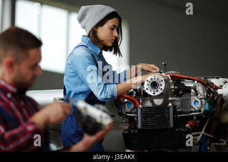 Female Mechanic Inspecting Engine in Workshop Stock Photo