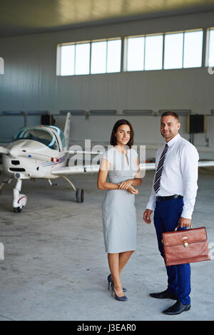 Smiling Business Couple in Airport Hangar Stock Photo
